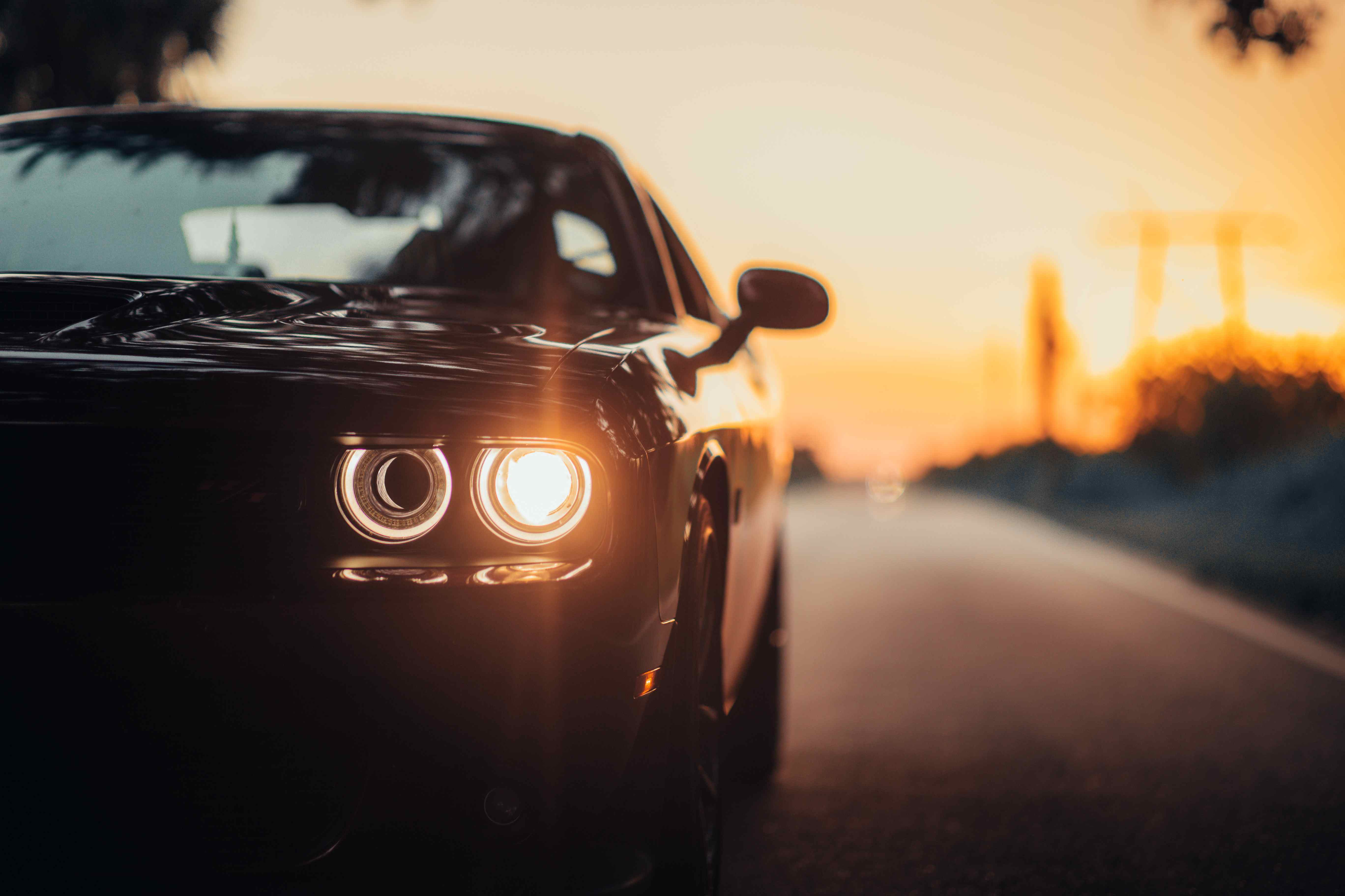 Luxury car at sunset with glowing headlights